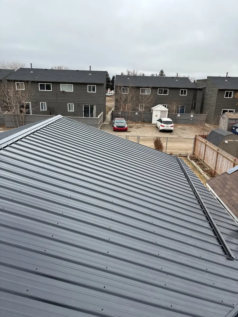 Long run of grey metal roofing panels over a residential garage and house